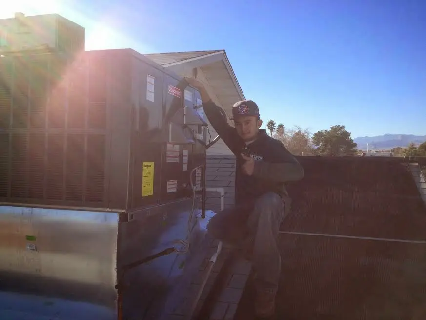 HVAC technician performing Air Duct Cleaning on a rooftop unit in Pineville